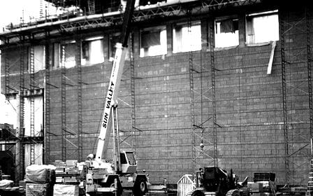 Construction site with a crane, scaffolding against a building, and materials on the ground, all part of Sun Valley Construction.