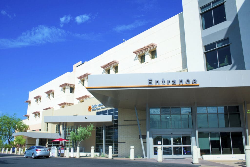 Modern building with an "entrance" sign above the door and a clear blue sky in the background.