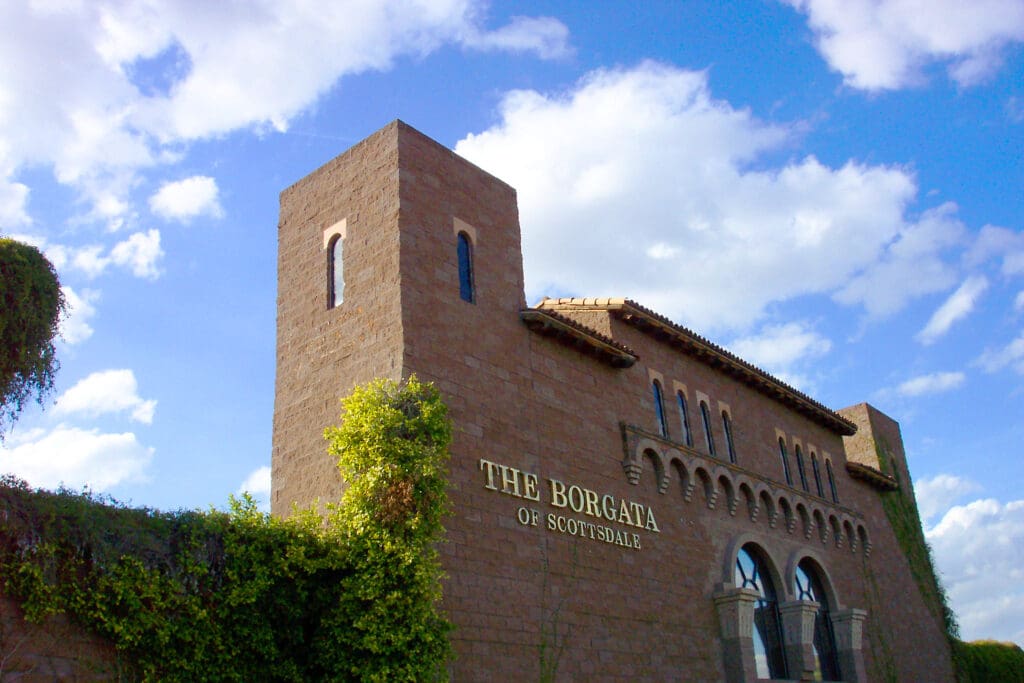 A sunlit photograph of the borgata of scottsdale building with a clear blue sky in the background.