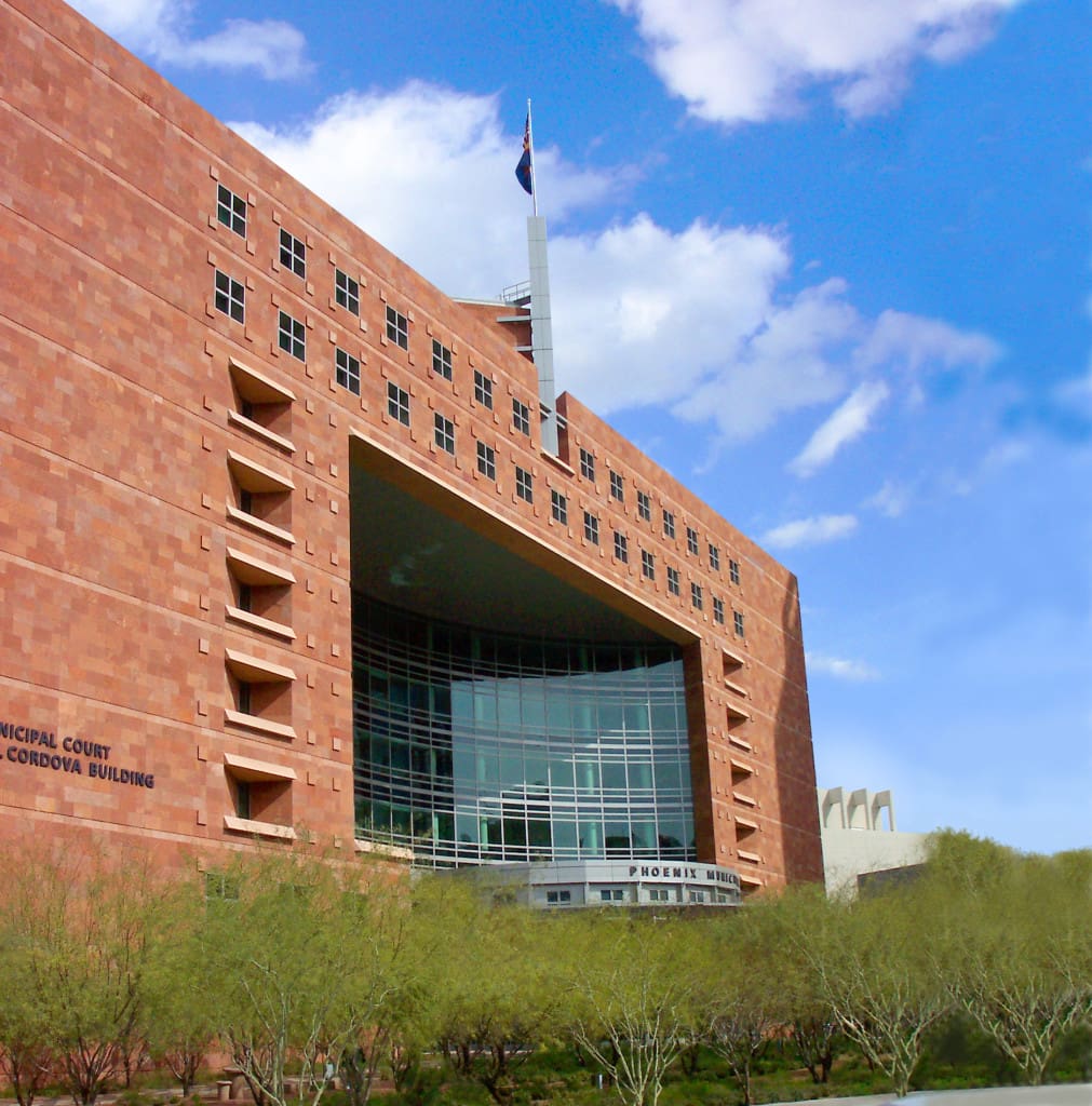 A modern courthouse building with a large glass entrance and a texas flag flying at the top.