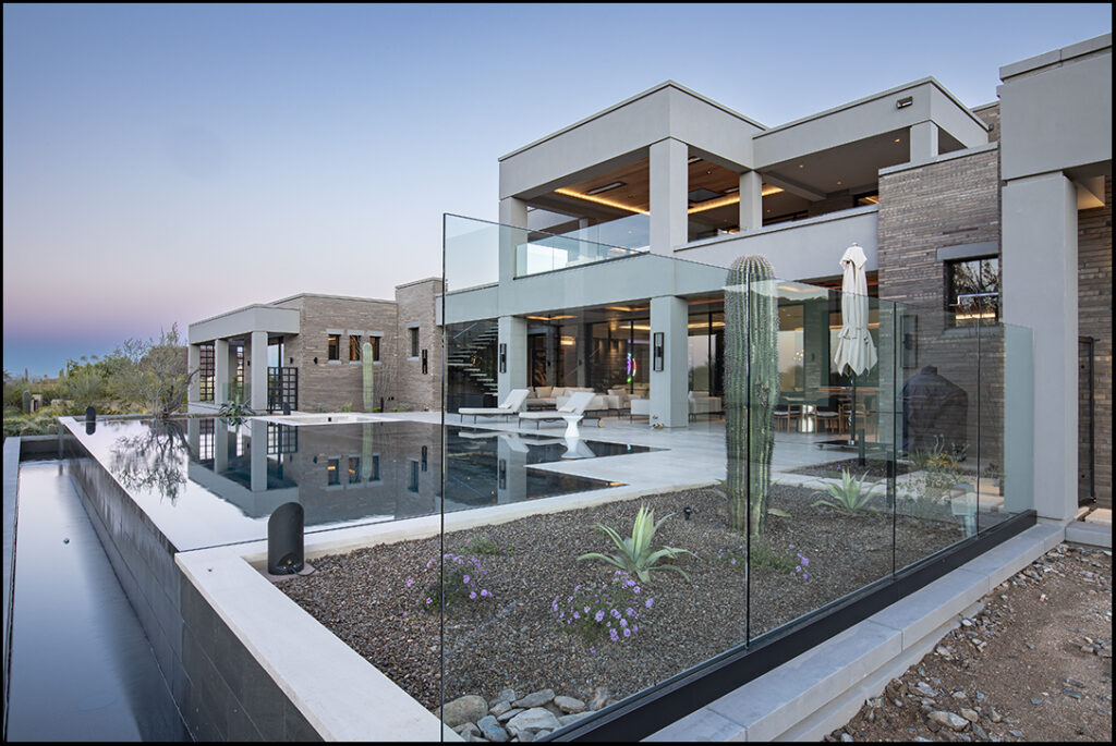 Residential luxury home with a pool at dusk.