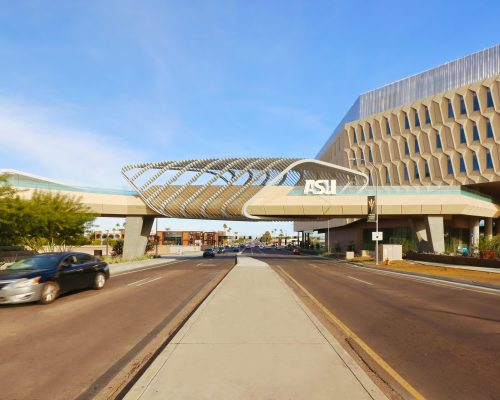 Modern arizona state university building with distinctive architectural design, featuring a large asu logo, under a clear blue sky.