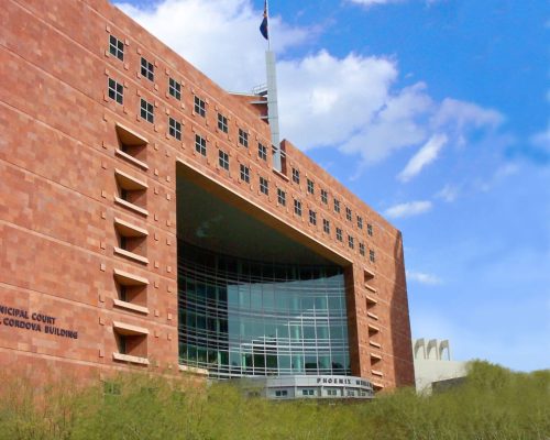 A modern courthouse building with a large glass entrance and a texas flag flying at the top.