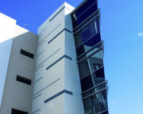 A modern building with an angular glass feature against a clear blue sky.