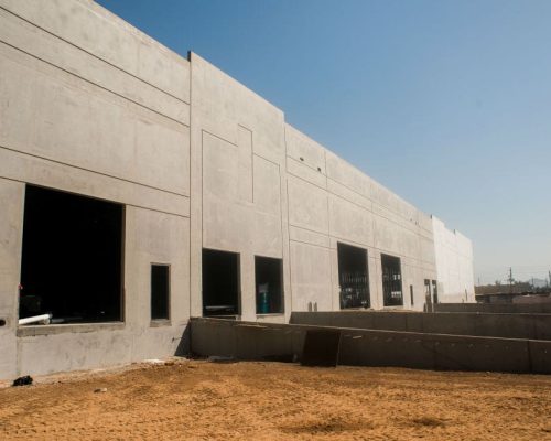 Exterior view of a concrete building under construction with unfinished openings for windows and doors.