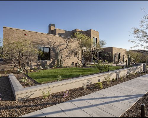 Modern residential desert home with landscaped garden at dusk.